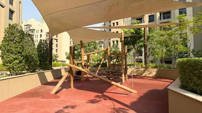 a playground with an umbrella on a patio at Elegant Stay with Pool & Gym Near Iconic Landmarks in Dubai