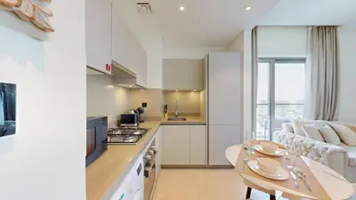 a kitchen and living room with a table and a couch at Creek Vistas - Elegant One Bedroom in Meydan in Dubai
