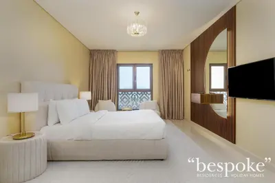 a bedroom with a white bed and a television at Bespoke Holiday Homes - Spacious 2BR Luxury Apartment with Stunning Palm Views, Balqis in Dubai
