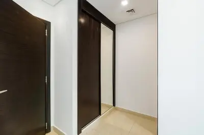 a hallway with a wooden door and white walls at Neat and Cozy 2BR plus Kids Room - 7min to Dubai Mall in Dubai