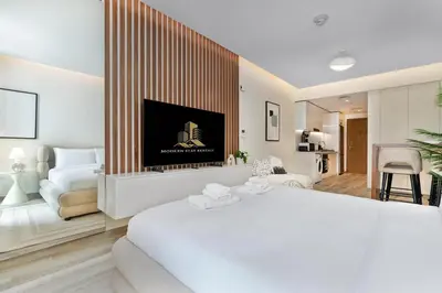 a white bedroom with a large bed and a living room at Cloud 18 Studio - Business Bay in Dubai
