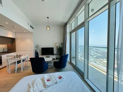 a bedroom with a bed and a kitchen with a view at Sophisticated Fully Furnished and Family-Friendly in Dubai