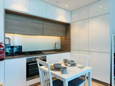 a white kitchen with a white table and chairs at Sophisticated Fully Furnished and Family-Friendly in Dubai