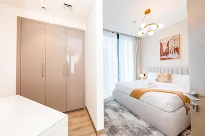 a white bedroom with a bed and a closet at Modern Living with Skyline Views in Hartland in Dubai