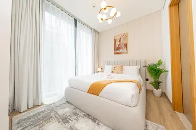 a bedroom with a white bed and a large window at Modern Living with Skyline Views in Hartland in Dubai