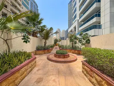 a walkway in the middle of a building with palm trees at 2BR with Marina Views - Near JBR Beach & Dubai Eye in Dubai