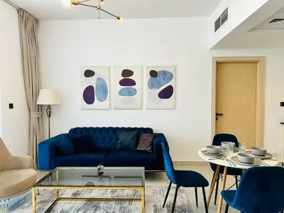 a living room with a blue couch and a table at Fully Furnished and High Floor Unit in Al Jaddaf in Dubai