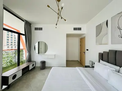 a white bedroom with a large bed and a television at Fully Furnished and High Floor Unit in Al Jaddaf in Dubai