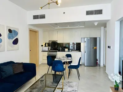 a living room with a table and chairs and a kitchen at Fully Furnished and High Floor Unit in Al Jaddaf in Dubai