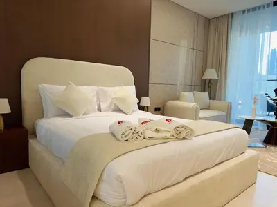 a bedroom with a large white bed with towels on it at Brand New with Private Jacuzzi in Dubai