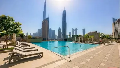 a swimming pool with lounge chairs and a city skyline at Zabeel View I Fully Furnished I Prime Location in Dubai