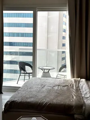 a bedroom with a large window with a table and chairs at Best Canal View Studio in AG Tower Business Bay in Sabkhah