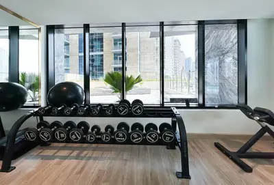 a gym with a bench in front of a window at 1-Bedroom Apartment in Downtown with Pool View in Dubai