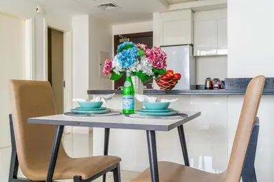 a table with two chairs and a vase with flowers at The Smart Concierge - Damac 108 in Dubai