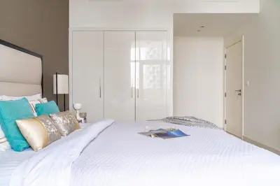 a bedroom with a white bed with a book on it at The Smart Concierge - Damac 108 in Dubai