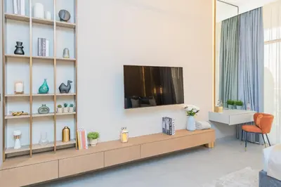 a living room with a tv on a wall at Escape24 Cozy Studio with Infinity Pool in JVC in Dubai