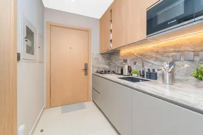 a kitchen with a sink and a wooden door at Escape24 Cozy Studio with Infinity Pool in JVC in Dubai