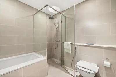 a bathroom with a shower and a toilet and a tub at Jumeirah Waterfront Residences in Dubai