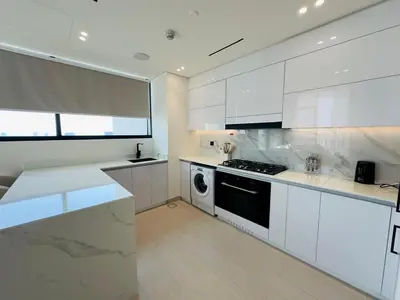 a white kitchen with a stove and a dishwasher at High-End Furnished Homey Elegant with Private Pool in Dubai