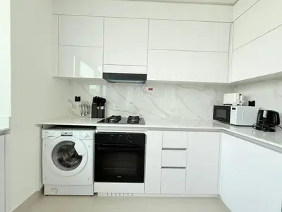 a white kitchen with a washing machine in it at Brand New with Installed Private Pool in Balcony in Dubai