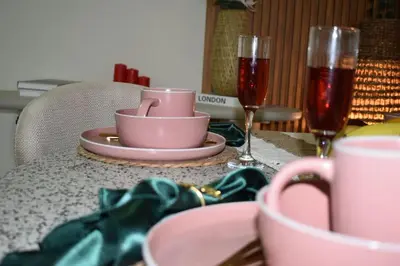 a table with a pink cup and plates and wine glasses at Cozy 2BR -Near JBR Beach &Metro in Dubai