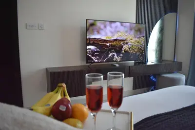 two glasses of wine sitting on a table with fruit at Cozy 2BR -Near JBR Beach &Metro in Dubai