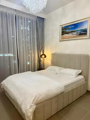 a bedroom with a large white bed and a chandelier at Giramondo Forte Tower 1 in Dubai