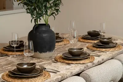 a table with plates and a vase on top of it at Seraya Residence 21 - 4BDR - Cozy terrace with Burj Views in Dubai