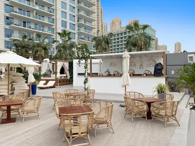 an outdoor patio with tables and chairs and umbrellas at Stylish 1BR Apartment in JBR with Beach Access & Dubai Marina Views in Dubai