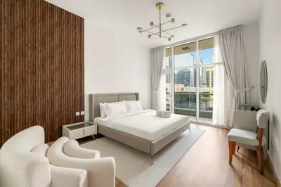 a white bedroom with a bed and two chairs at Dubai 1BR City Views, Near Downtown Dining, Culture & Attractions in Dubai