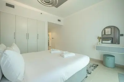 a white bedroom with a bed and a mirror at Zapbed House-Stylish 2 BR in May Residence Block 1 -JVC in Dubai