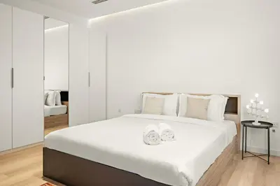 a white bedroom with a large bed with two towels at 2BR Dubai City Skyline View Near Marina Walk Dining Shops & JBR in Dubai