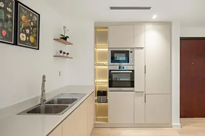 a white kitchen with a sink and a refrigerator at 2BR Dubai City Skyline View Near Marina Walk Dining Shops & JBR in Dubai