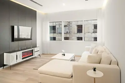 a white living room with a white couch and a tv at 2BR Dubai City Skyline View Near Marina Walk Dining Shops & JBR in Dubai