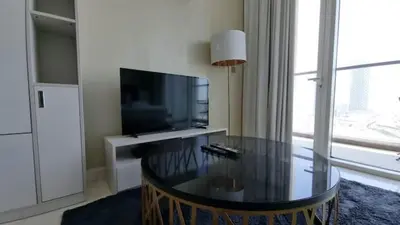 a living room with a table and a television at Business Bay, Compact, Modern Studio Dubai in Dubai