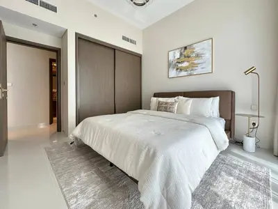 a bedroom with a large bed with a wooden headboard at Modern & Cozy 1BR with Great Amenities, Grand Bleu in Dubai