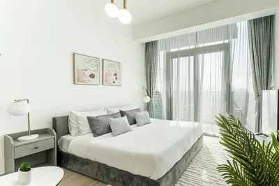 a white bedroom with a bed and a window at HAVN - High Floor Studio in Bloom Towers, JVC in Dubai