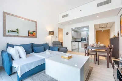 a living room with a blue couch and a table at Urban Comfort 1Bedroom with Pool View in Oxford in Dubai
