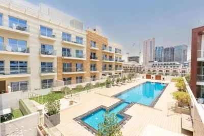 an apartment patio with a swimming pool in front of a building at Urban Comfort 1Bedroom with Pool View in Oxford in Dubai