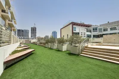 a green lawn on the side of a building at Urban Comfort 1Bedroom with Pool View in Oxford in Dubai