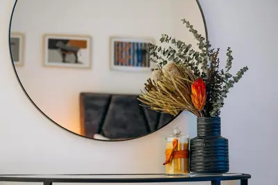 a table with a mirror and a vase with flowers at Amazing brand new 2BR - Business Bay-Binghatti in Dubai