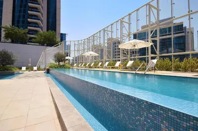 a swimming pool with chairs and umbrellas in a building at Luxurious Lake View 1BR - Business Bay - Pool - Gym in Dubai