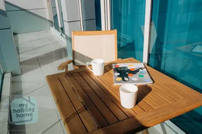 a table with a book and two cups on it at Beautiful 1BR-Fully Furnished- Balcony-Pool & Gym in Dubai