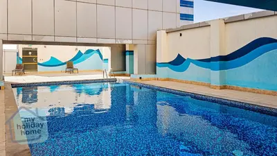 a swimming pool with blue water in front of a building at Beautiful 1BR-Fully Furnished- Balcony-Pool & Gym in Dubai