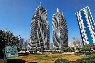 three tall buildings in a city with a park at Beautiful 1BR-Fully Furnished- Balcony-Pool & Gym in Dubai
