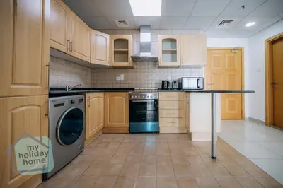 a kitchen with wooden cabinets and a dishwasher at Beautiful 1BR-Fully Furnished- Balcony-Pool & Gym in Dubai