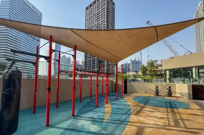 awning over a playground in a city with tall buildings at Bright 1 Bedroom with Burj Khalifa view in Peninsula in Dubai