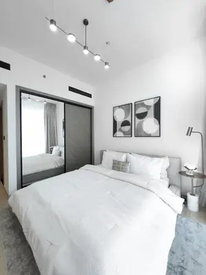 a white bedroom with a large bed and a mirror at Stunning 1BR in Binghatti Corner, JVC in Dubai