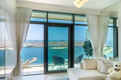 a living room with a white couch and a large window at Most Luxurious 2BR Apt Beach Access & Palm View in Dubai