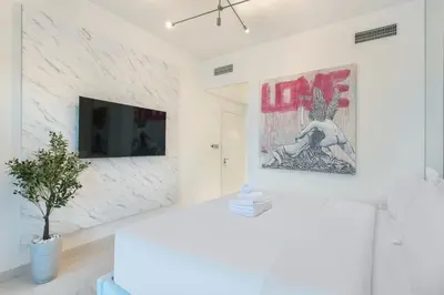 a living room with a tv on a white wall at Most Luxurious 2BR Apt Beach Access & Palm View in Dubai